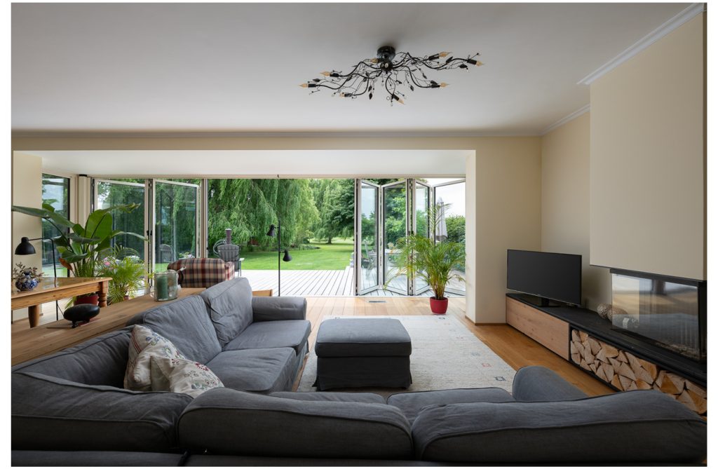 Moderne serre met glazen vouwwand en uitzicht op groene tuin