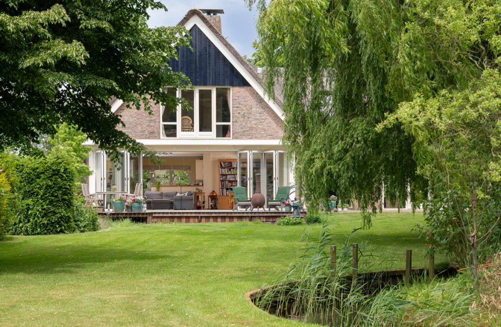 Strakke serre met glazen vouwwand en houten vlonder aan tuinzijde