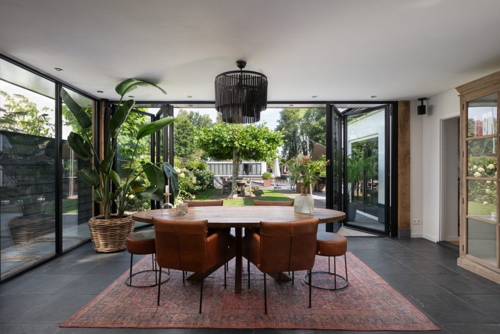 Panoramisch zicht vanuit de serreaanbouw met elegante vouwwand en groene omgeving