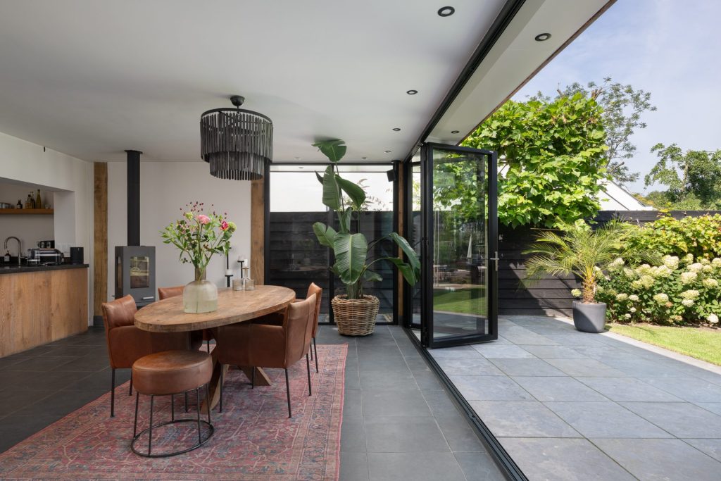 Moderne vouwwand van de serre geopend naar een terras en het water