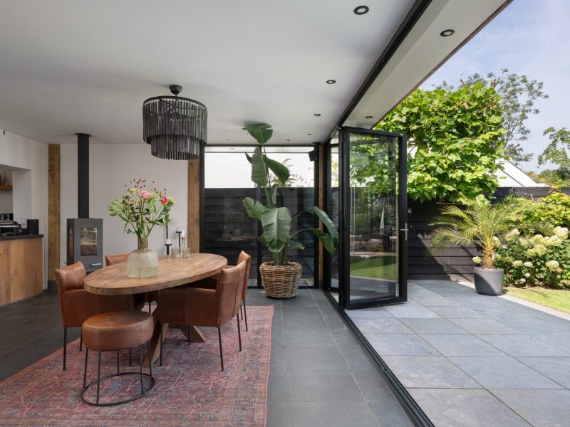 Moderne vouwwand van de serre geopend naar een terras en het water