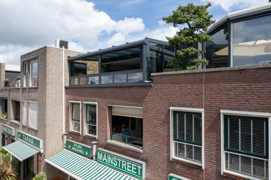 Moderne glazen serre als verlengstuk van de bovenverdieping