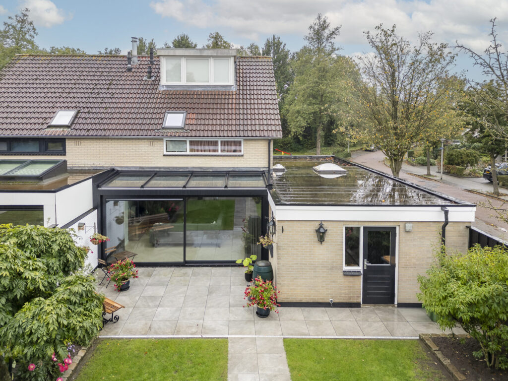 Vernieuwde serre met grote glaspartijen en een open verbinding tussen woonkamer en tuin.